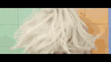 a woman 's hair is blowing in the wind in front of a colorful wall