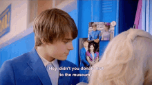 a boy in a blue suit talks to a girl in a white headband