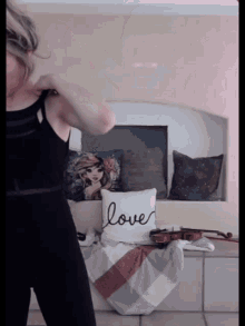 a woman stands in front of a fireplace with a pillow that says love