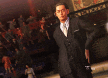 a man in a suit and tie is standing in front of a sign that says start