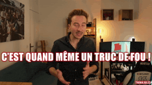 a man in a black shirt is standing in front of a sign that says c'est quand meme un truc de fou