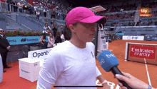 a woman wearing a pink hat is being interviewed by a tv camera