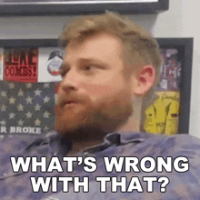 a man with a beard is sitting in front of a wall with stickers on it .