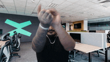 a man giving the middle finger in an office with a green x on the wall