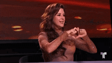 a woman making a heart shape with her hands in front of a tv screen
