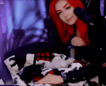 a woman with red hair is sitting in front of a microphone while holding a cat .