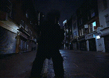 a person walking down a dark street at night with a sign that says ' a ' on it