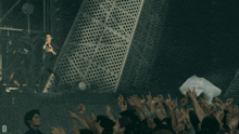 a man singing into a microphone in front of a perforated metal wall with the letter d on it