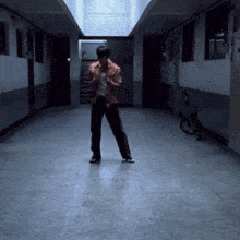 a man is standing in a hallway with a bicycle parked in the background