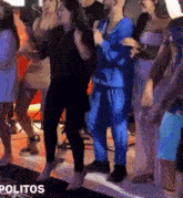 a group of people are dancing in a room with the word politios in the corner .