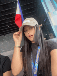 a woman wearing a hat and a lanyard with the word college on it looks at the camera