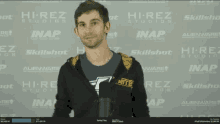 a man stands in front of a wall that says hi-rez