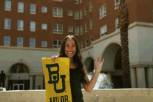 a woman holds a yellow banner with the letter b on it