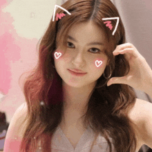 a woman with cat ears on her head making a heart shape with her hand