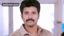 a man with a mustache is smiling while wearing a brown shirt .