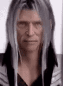 a man with long gray hair is wearing a black jacket .