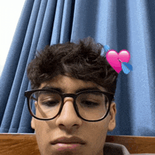 a young man with glasses and a pink heart on his head