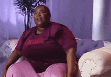 a woman is sitting on a couch wearing a purple shirt that says daddy