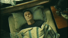 a man laying on a bed with a green and white blanket