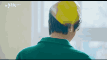 a man wearing a green shirt and a yellow hat is looking at the camera .