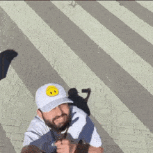a person wearing a hat and sunglasses is walking across a brick crosswalk .