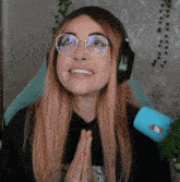 a woman wearing glasses and headphones is smiling and praying