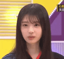 a close up of a woman 's face with long hair and bangs making a funny face .