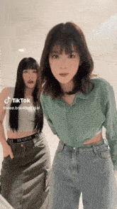 two women are standing next to each other and one of them is wearing a crop top .