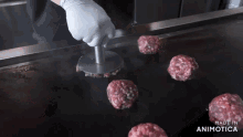 a hamburger patty is being pressed on a grill with the words made in animotica in the corner