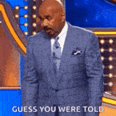 a man in a suit and tie is standing on a stage with the words `` guess you were told '' .