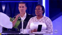a man and a woman are sitting at a table with a microphone .