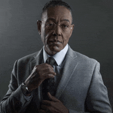 a man in a suit adjusts his tie