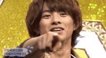 a close up of a young man pointing at the camera .