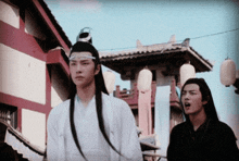 a man with long hair stands next to another man