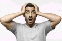 a man with a surprised look on his face holds his head in his hands