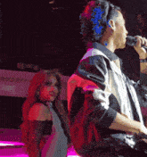 a man is singing into a microphone while a woman stands behind him