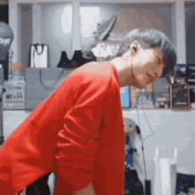 a man wearing a red sweater and earphones is standing in a room .