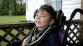 a young boy in a wheelchair has a scarf around his neck that says ' autism '