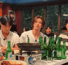 a group of people sitting at a table with green bottles of tera beer