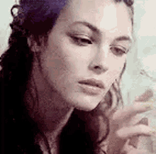 a close up of a woman smoking a cigarette while looking at her phone .