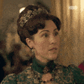 a woman wearing a green dress and a tiara with hbo on the bottom