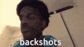 a man is making a funny face and the words backshots are visible behind him