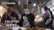 a little girl is sitting at a table with a plate of food and a man holding a knife ..