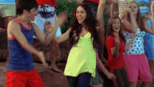 a group of young people are dancing together and one of them is wearing a yellow top