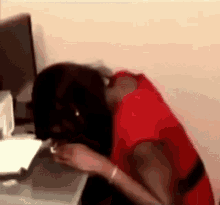 a woman in a red dress is sitting at a desk in front of a computer