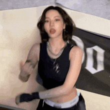 a woman in a black tank top is dancing in front of a black and white banner .