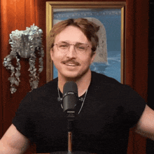 a man with glasses and a mustache is standing in front of a shure microphone