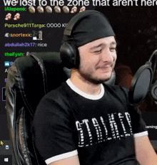 a man wearing headphones and a headband is crying while sitting in front of a microphone .