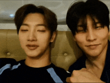 two young men are sitting next to each other on a couch with their eyes closed