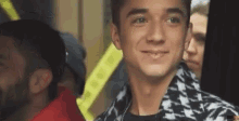 a young man is smiling and looking at the camera while standing in a crowd .